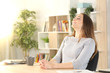 © PheelingsMedia - Woman breathing fresh air sitting on a desk at home