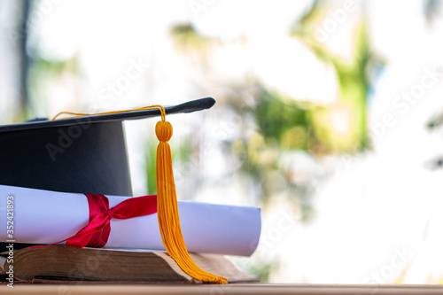 A black graduation cap and a certificate placed on an old book