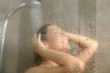 © Antonioguillem - Happy woman having shower behind glass on a bathroom