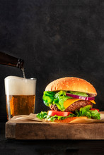 Burger And Beer. Cheeseburger With Beef, Cheese, Onion, Tomato, And Green Salad, A Side View On A Dark Background With A Place For Text. Selective Focus