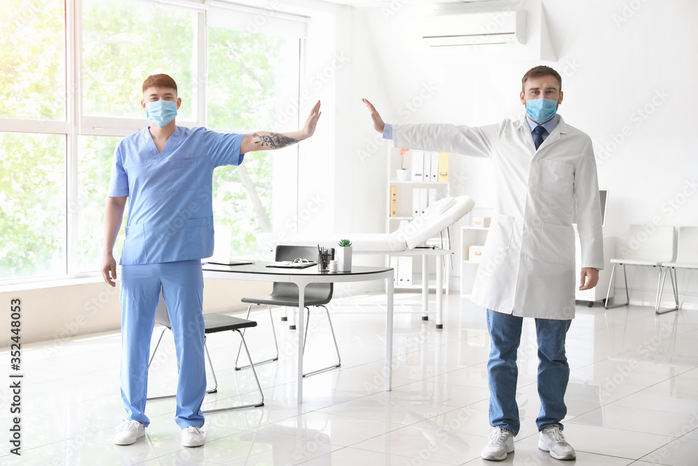 Doctors wearing protective masks in clinic. Concept of social distance