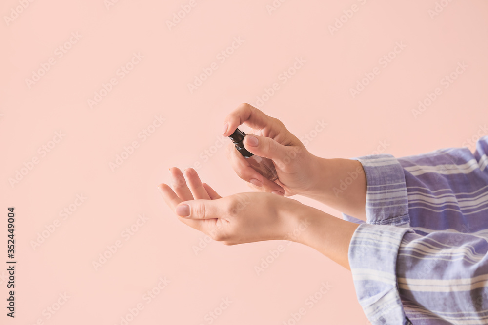 Woman applying disinfectant on her hands against color background