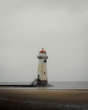 A An Old Lighthouse On A Stormy Bleak Beach. Moody Atmospheric Beach With No People. 