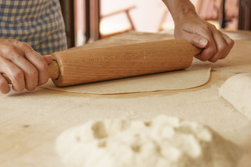 Close up process of homemade vegan farfalle pasta with durum wheat flour. The cook uses a rolling pin to stretch the dough, traditional Italian pasta, the woman cooks the food in the kitchen