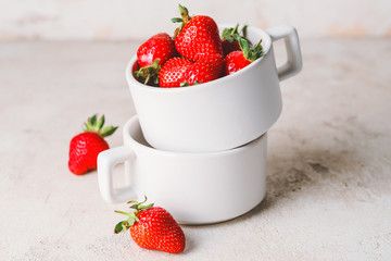 Cups with ripe strawberry on light table