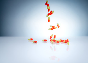 Wall Mural - Yellow-orange capsules pill falling down on white table. Pharmaceutical industry. Drug interactions, side effect, and adverse drug reaction (ADR) background. Drug overuse concept. Global healthcare.