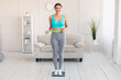 © Prostock-studio - Smiling Girl Measuring Thin Waist Standing On Weight-Scales At Home