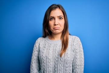 Sticker - Beautiful young woman wearing casual wool sweater standing over blue isolated background depressed and worry for distress, crying angry and afraid. Sad expression.