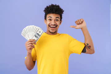 Canvas Print - Photo of african american man holding dollars and pointing thumb himself