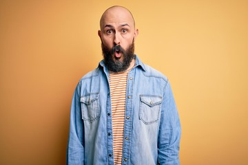 Canvas Print - Handsome bald man with beard wearing casual denim jacket and striped t-shirt afraid and shocked with surprise expression, fear and excited face.