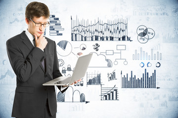 Wall Mural - Pensive businessman with laptop and drawing global marketing plan