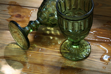 Two wine glasses of green color on a wooden table