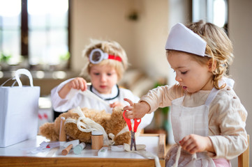 two small children with doctor uniforms indoors at home, playing.