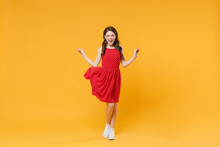 Cheerful Funny Young Brunette Woman Girl In Red Summer Dress Posing Isolated On Yellow Wall Background Studio Portrait. People Sincere Emotions Lifestyle Concept. Mock Up Copy Space. Spreading Hands.
