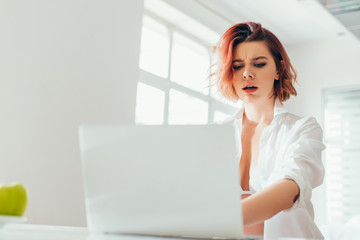 Wall Mural - attractive confused girl using laptop on kitchen during quarantine