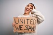 © Krakenimages.com - Young beautiful blonde woman with blue eyes asking for united stand holding banner with happy face smiling doing ok sign with hand on eye looking through fingers