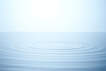 Water ripples, splash. Beautiful wide water surface. Horizon, light blue background. Calm and smooth water.