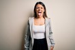 © Krakenimages.com - Young beautiful brunette sportswoman wearing sportswoman training over white background sticking tongue out happy with funny expression. Emotion concept.