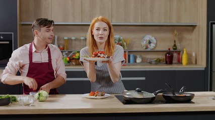 Wall Mural - Cooking show hosts chefs, male and female, showing cooked dish into camera. Morning TV cooking programme