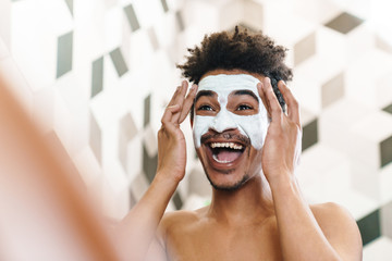 Poster - Photo of african american man with mask on his face looking at mirror