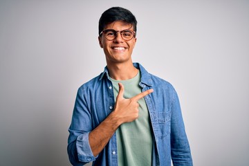 Canvas Print - Young handsome man wearing casual shirt and glasses over isolated white background cheerful with a smile of face pointing with hand and finger up to the side with happy and natural expression on face