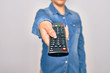© Krakenimages.com - Woman changing television channel holding tv remote control. Standing over isolated white background