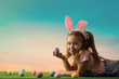 © producer - adorable little child girl with bunny ears on Easter day. kid with Easter eggs on the lawn.