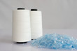 © Recycle Man - Bottle flake,PET bottle flake,Plastic bottle crushed,Small pieces of cut blue plastic bottles & Raw White Polyester FDY Yarn spool with white background