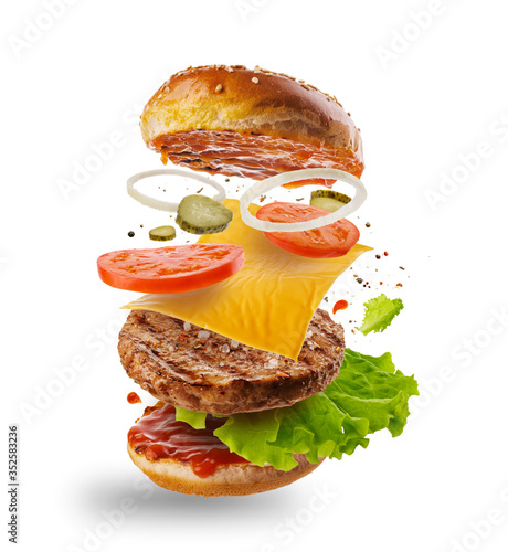 Burger with flying elements. Delicious burger with flying ingredients isolated on white background. Flying Burger Slices.