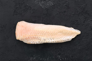 Raw shallow-water hake fillet on black background