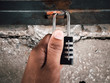 © sukan - The hand is holding the padlock. Numeric locking system locking iron door In order to prevent loss of internal assets. Safety system