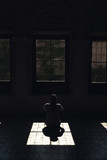 Fototapeta Morze - mujer solitaria mirando por la luz que entra por la ventana en un cuarto oscuro