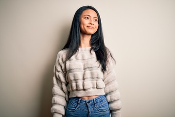 Wall Mural - Young beautiful chinese woman wearing casual sweater over isolated white background looking away to side with smile on face, natural expression. Laughing confident.