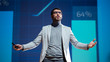 © Gorodenkoff - On-Stage Speaker Greets Audience, Presentation of Technological Device, Shows Infographics Animation on Big Screen. Auditorium Hall Live Event, Product Release, Start-up Conference. Low Angle