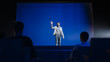 © Gorodenkoff - Successful Speaker Stands on Stage and Does New Product Presentation. Presenter / Motivational Speaker Greets Audience in Conference Hall, Starts His Entrepreneurship Presentation / Talk / Live Event