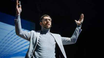 Portrait of Inspirational Innovative Speaker, Talking about Happiness, Self, Success, Empowerment, Efficiency and How to Be More Productive Self. Large Conference Hall with Cinematographic Light