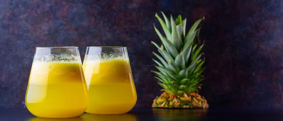 Wall Mural - Pineapple cocktail on a dark background. Cold pineapple cocktail with mint. Summer tropical cocktail on a black background. Healthy drink