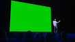 © Gorodenkoff - Software Startup Founder Does Presentation of New Product to the Audience, Behind Him Movie Theater with Green Screen, Mock-up, Chroma Key. Business Conference Live Event or Device Reveal