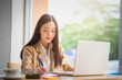 © nuttawutnuy - Portrait of Young asian businesswoman sitting indoors in cafe using digital tablet with coffee. Business success concept.