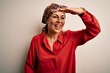 © Krakenimages.com - Middle age brunette woman wearing handkerchief on head and shirt over white background very happy and smiling looking far away with hand over head. Searching concept.
