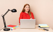 © luismolinero - Young student woman in a workplace with a laptop with confuse face expression