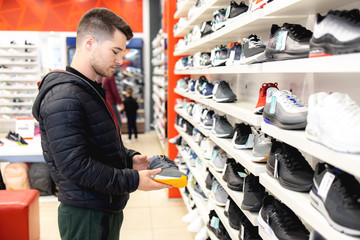 Young man looking for sports equipment at sports shop