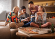 © BalanceFormCreative - Group of friends making fun at the home party.They sitting in living room and eating pizza.