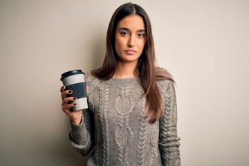 Wall Mural - Young beautiful brunette woman drinking glass of coffee over isolated white background with a confident expression on smart face thinking serious