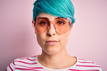 Sticker - Young beautiful woman with blue fashion hair wearing fanny glasses with hearts with a confident expression on smart face thinking serious