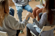 © Roman - cropped photo of young unrecognizable addicts gathered together in the club of anonymous drug users, people sit holding hands, pray for speedy recovery, support