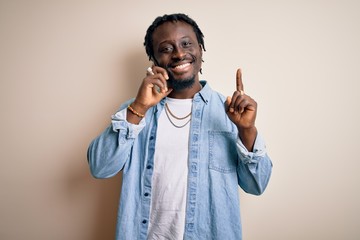 Sticker - African american man having conversation talking on the smartphone over white background surprised with an idea or question pointing finger with happy face, number one