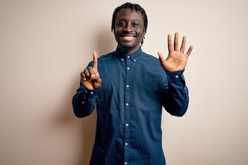 Sticker - Young handsome african american man wearing casual shirt standing over white background showing and pointing up with fingers number six while smiling confident and happy.