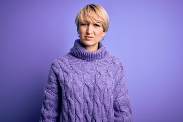 Sticker - Young blonde woman with short hair wearing winter turtleneck sweater over purple background skeptic and nervous, frowning upset because of problem. Negative person.