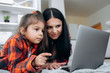 © Kateryna - Online shopping. Joyful and pretty caucasian mom and daughter are shopping online at home on the couch using a laptop. Nice time together at home
